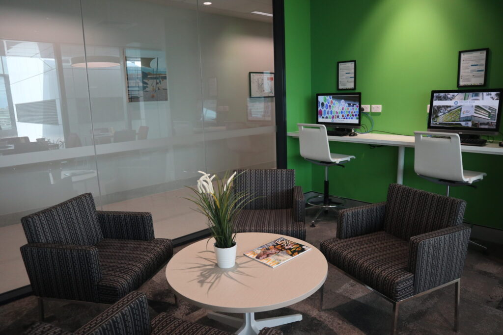 Photo of one lounge area with armchairs and computers and desks in the background
