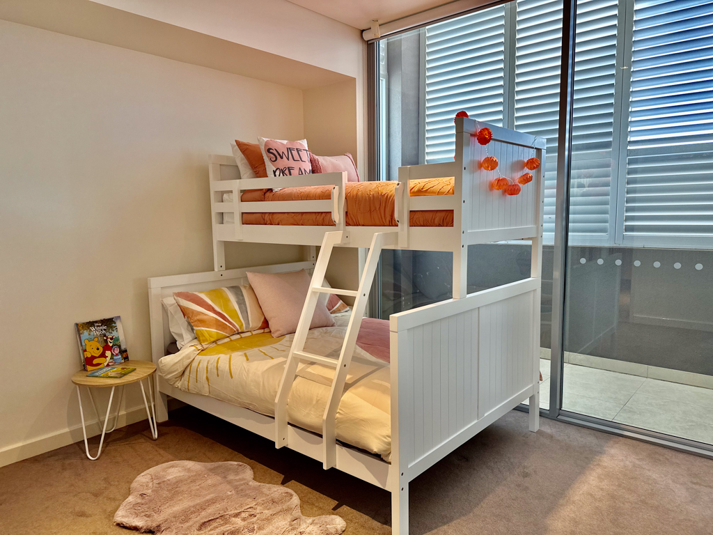 A photo of the second bedroom in the Ronald McDonald Family Retreat in Mandurah, with a bunk bed with a queen bed base and single bed upper bunk.