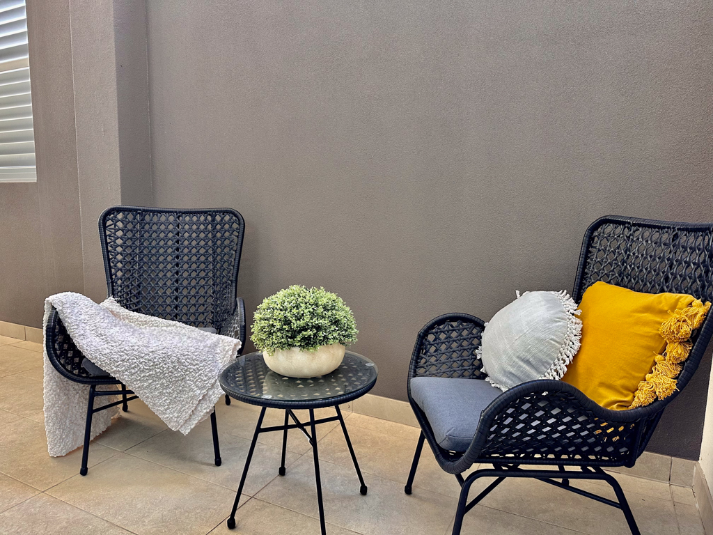 A photo of a small courtyard in the Ronald McDonald Family Retreat in Mandurah, with two lounging chairs and a side table.