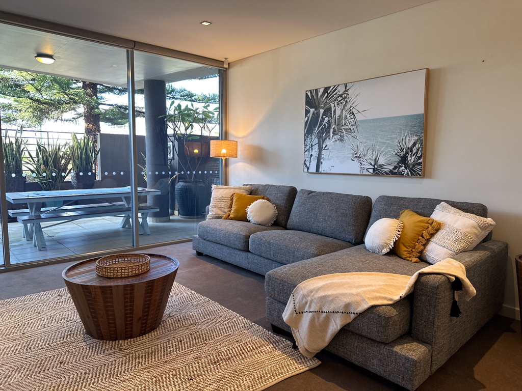 A photo of the loungeroom in the Ronald McDonald Family Retreat in Mandurah, showing a lounge, window and dining table on the patio outside.