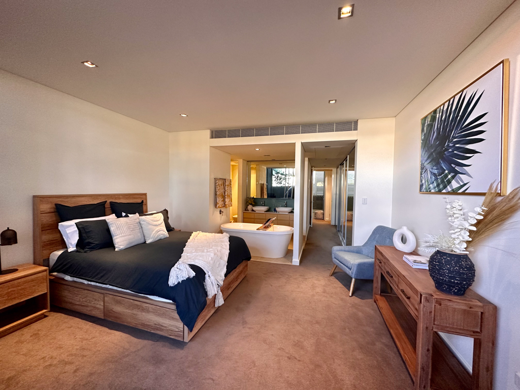 A photo of the Master Bedroom of the Ronald McDonald Family Retreat in Mandurah, showing a bed, chair and ensuite bathroom.