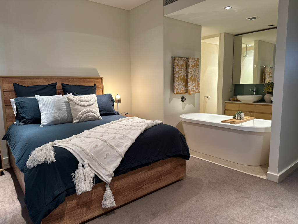 A photo of the Master Bedroom of the Ronald McDonald Family Retreat in Mandurah, showing a bed, chair and ensuite bathroom.