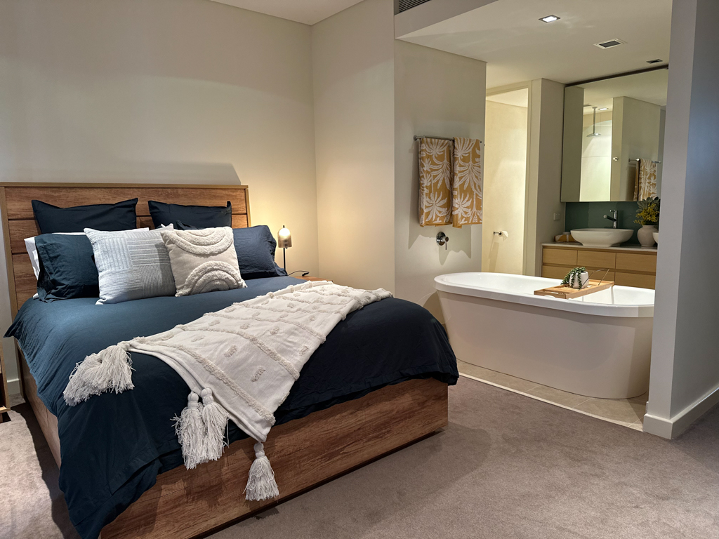 A photo of the Master Bedroom of the Ronald McDonald Family Retreat in Mandurah, showing a bed, chair and ensuite bathroom.