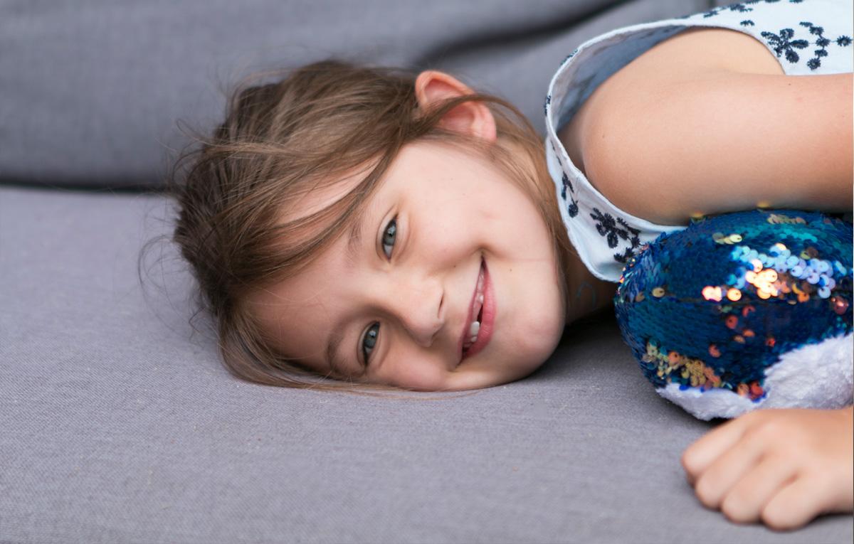 Photo of a child lying on her side and smiling